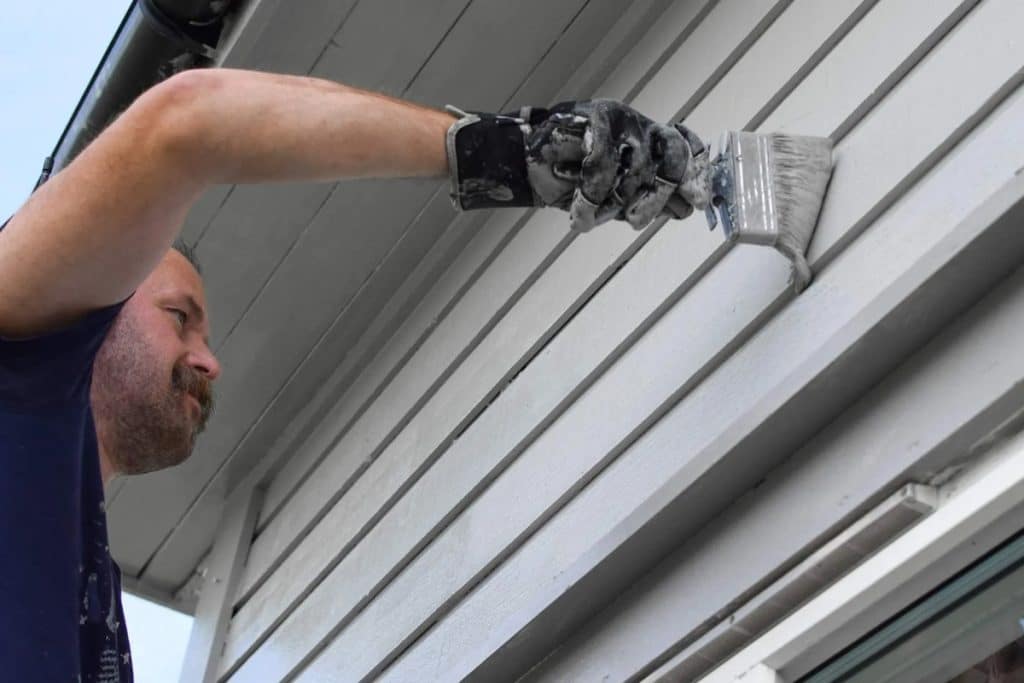 clean vinyl siding man paints the exterior wall