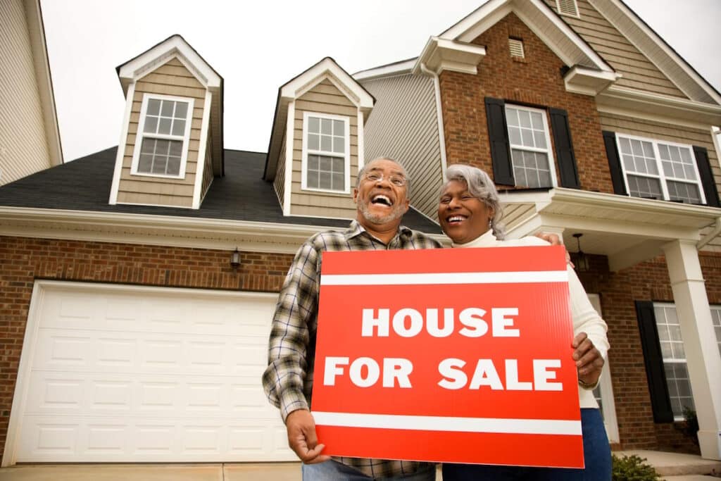 siding contractor couple holding for sale sign