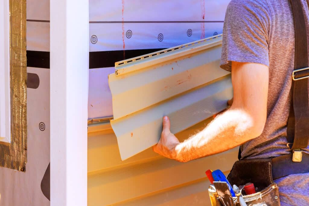 fiber cement siding vs vinyl siding worker installs siding on house
